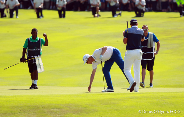 Winner, Mikko Ilonen's caddy punches the air as he bends to take his ball out of the 18th hole